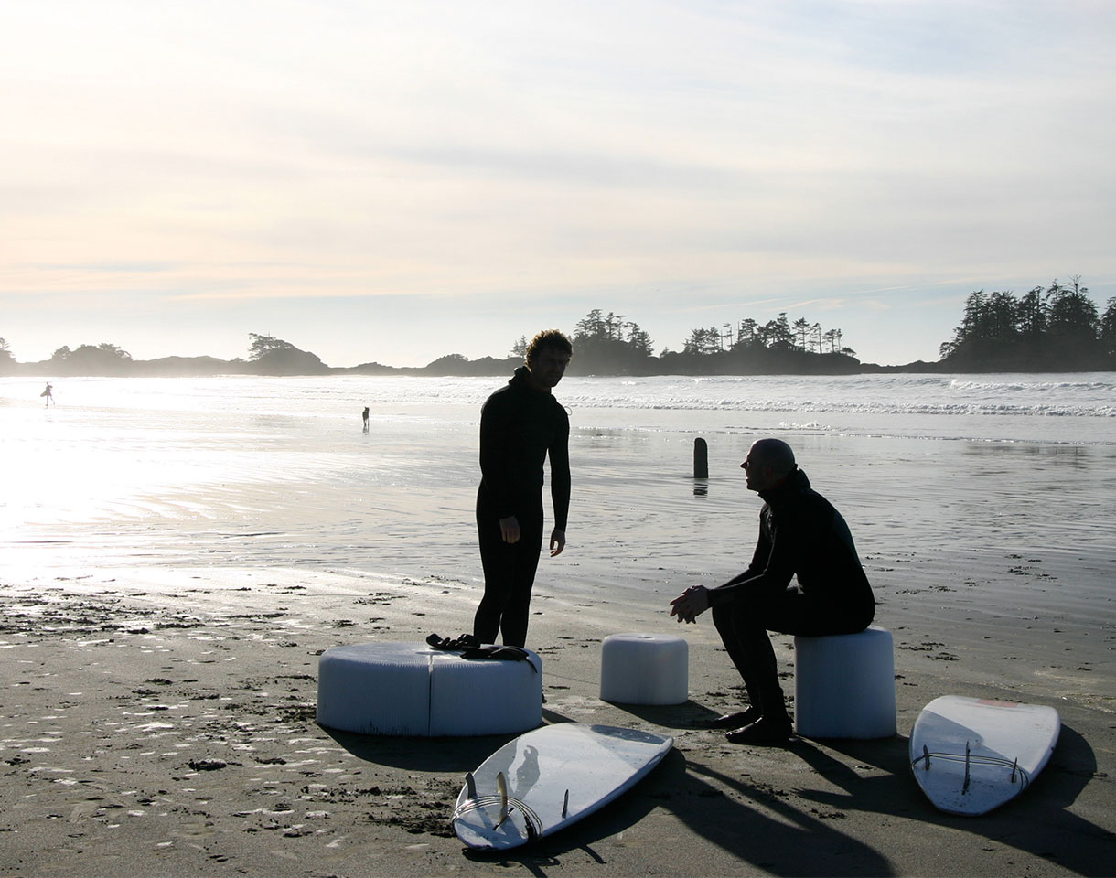 Surfers sit on softseating folding stools. Great beach furniture, this portable seating comes with carry tote. This is the water resistant textile version of original paper stool by molo.